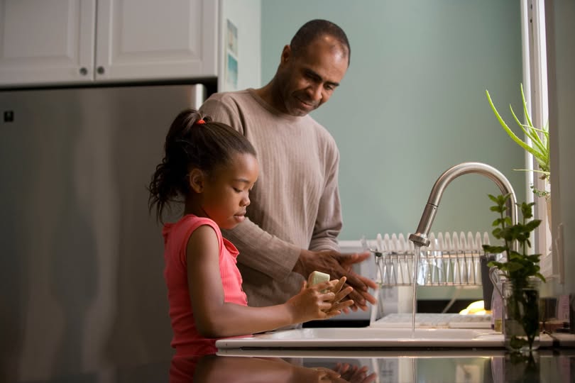 a father and daughter at the kitchen sink washing their hands together
