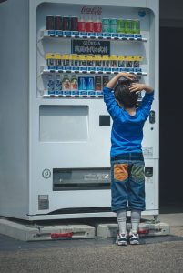 a young boy in front of a drinks vending machine. He is trying to choose from all the options available.